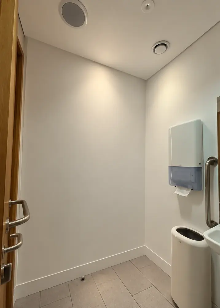 A plain white washroom corner before the work